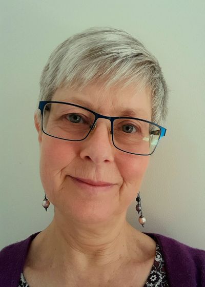 Smiling woman with short gray hair and glasses.