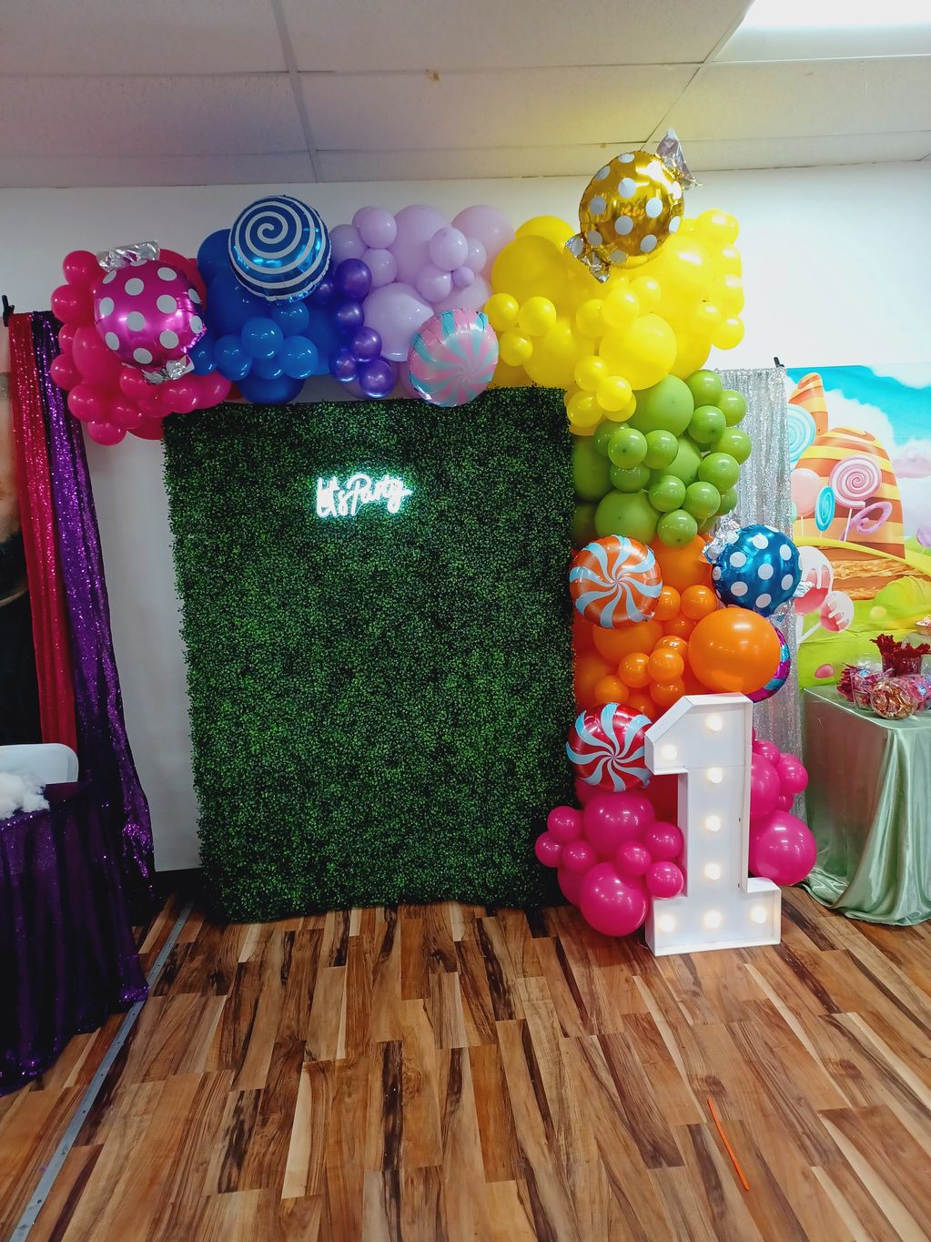 Colorful balloon decoration with a large number 1 and greenery backdrop.