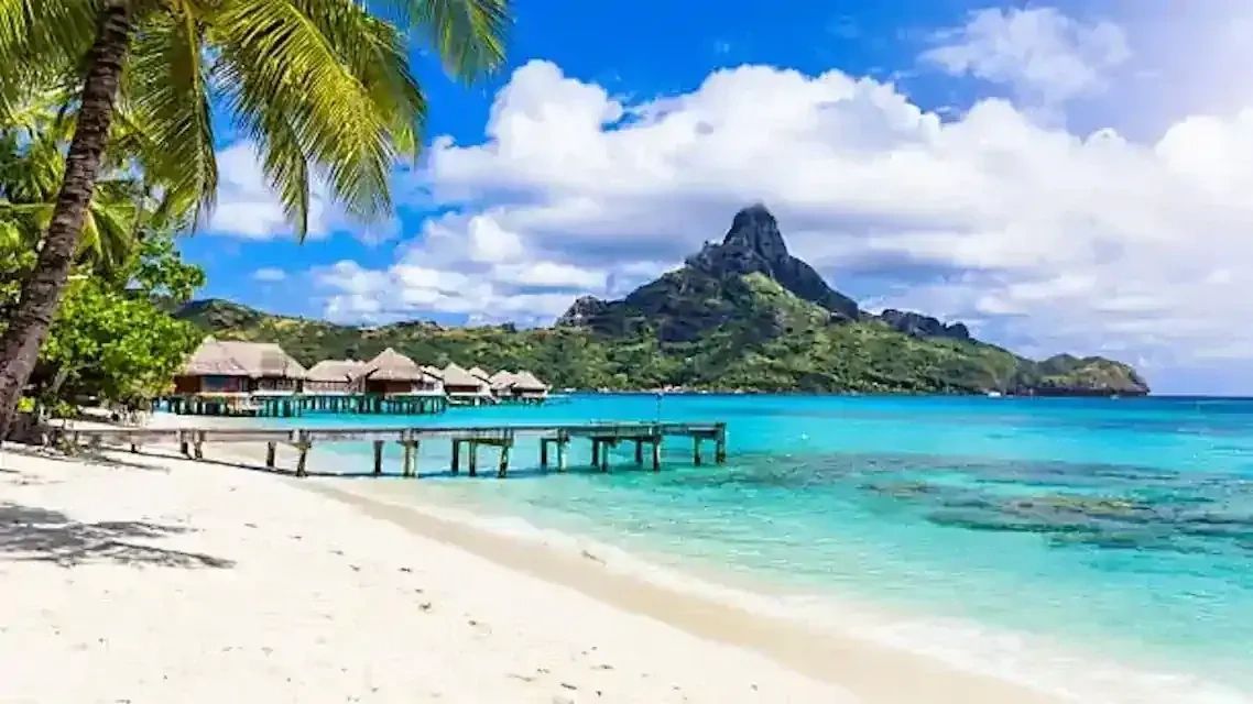 Tahiti overwater bungalows ina blue lagoon with a mountain inthe background