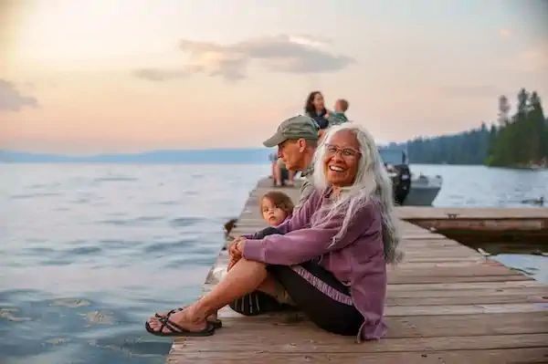 Family sitting on a dock by the lake at sunset.