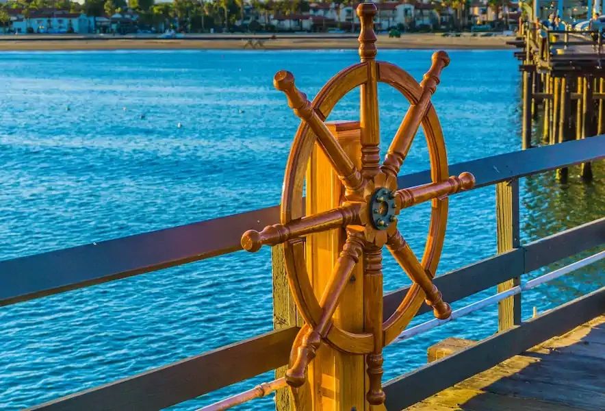 Wooden ship steering wheel on a pier overlooking the sea.