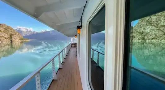 Scenic view from a boat on calm water surrounded by rocky mountains.