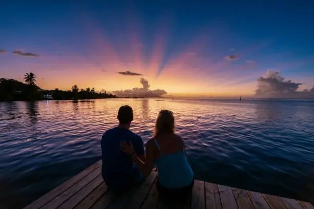 Couple watching sunset by the water on a dock.
