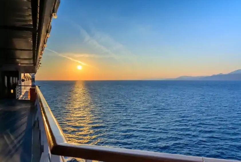 Sunset view from a ship's deck over the ocean.