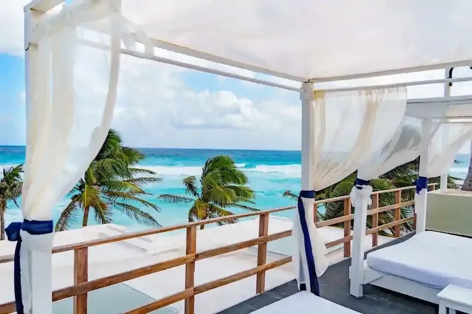 Boutique luxury resort suite balcony overlooking tropical palm trees and turquoise ocean waters