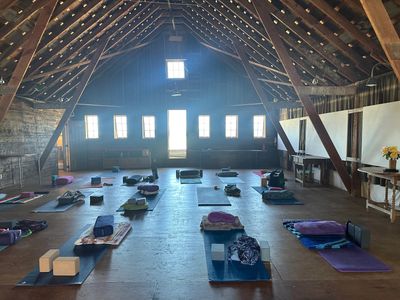 Spacious rustic barn set up for a yoga or meditation class with mats and props.