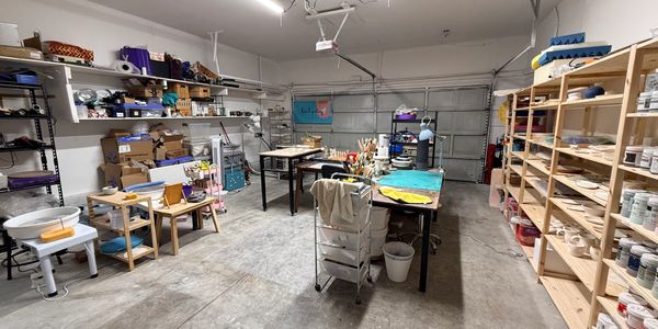 A spacious art studio with shelves, tables, and supplies organized for creative work.