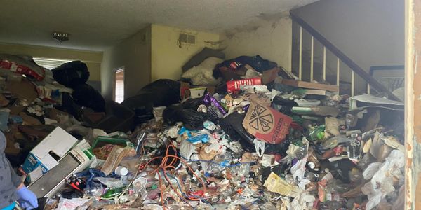 A cluttered room filled with a large pile of trash and discarded items.