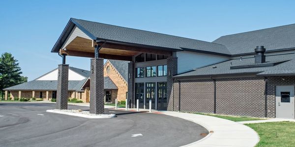 Modern building entrance with brick pillars and covered driveway.