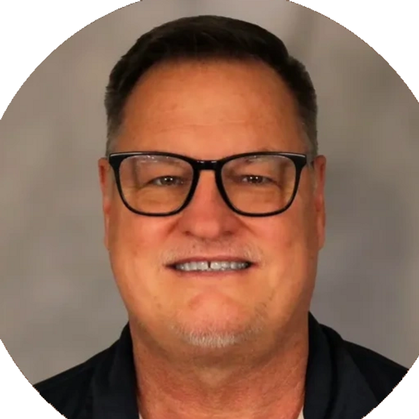 Smiling man with glasses and short hair in a circular frame.
