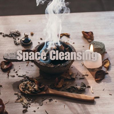 A smoldering bowl with incense and a candle for space cleansing ritual.
