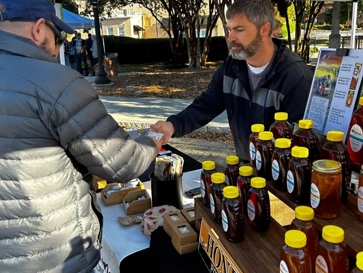 A man buying honey at an outdoor market.