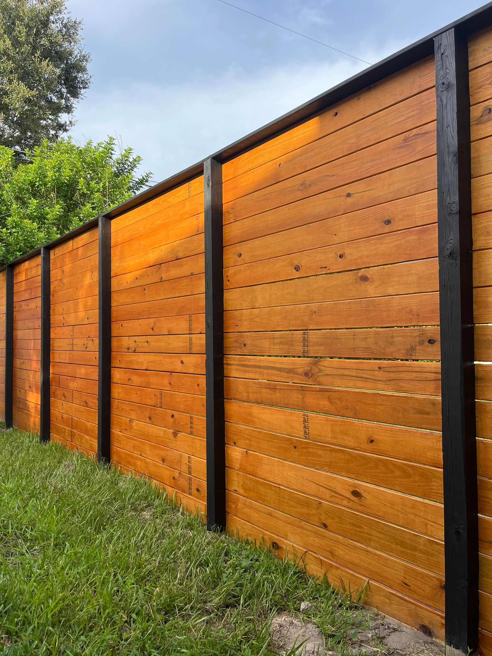 Horizontal deck board fence stained with semi transparent and posts painted black 