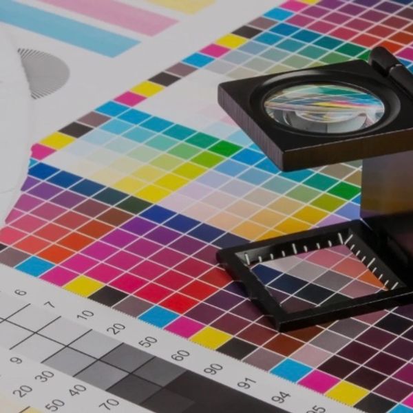 A color calibration chart with a magnifying glass on top for print quality inspection.