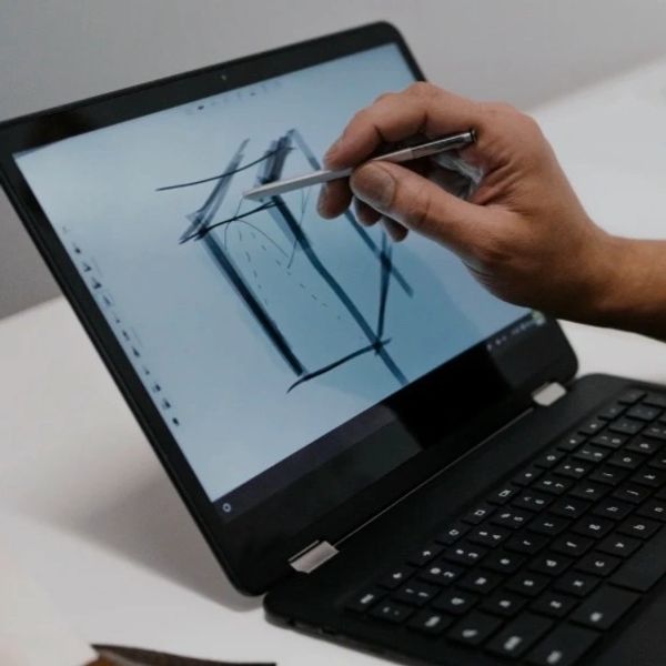 Person drawing with stylus on a convertible laptop screen.