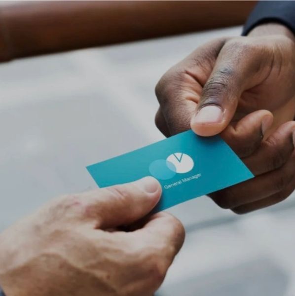 Two people exchanging a blue business card with a logo and text.