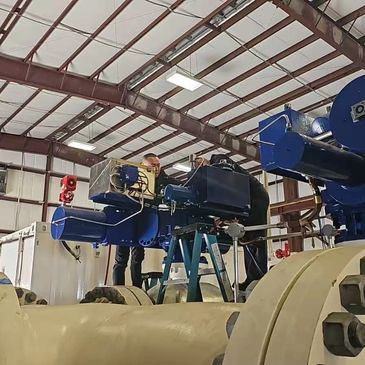 Technicians working on large industrial machinery inside a facility.