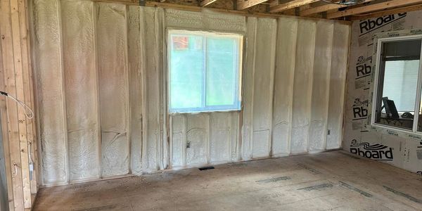 Interior of a room under construction with spray foam insulation on walls.