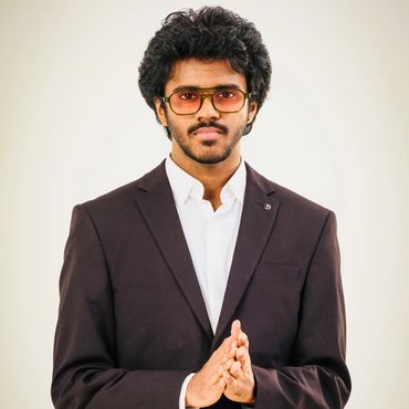 Young man in a black suit with glasses.
