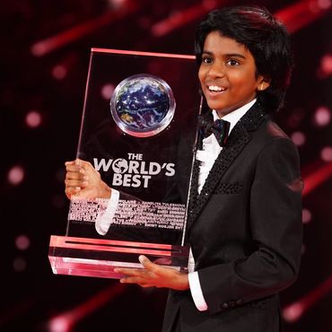 Smiling boy holding a large award trophy.