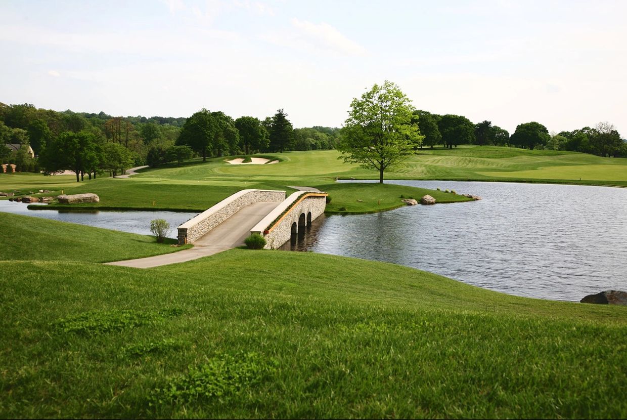 A peaceful golf course with a small stone bridge over water.
