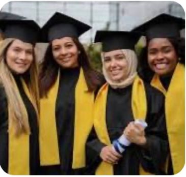 Four female graduates in caps and gowns celebrating.