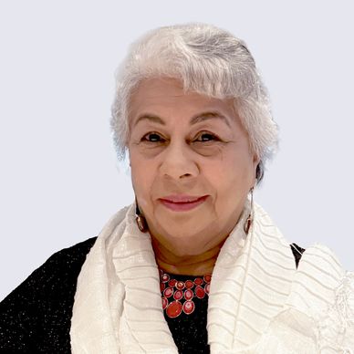 Smiling elderly woman with white hair and a white shawl.