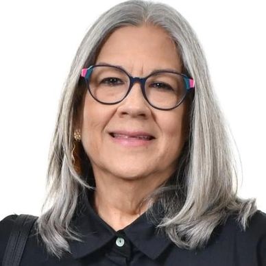 Smiling older woman with gray hair and glasses in black attire.