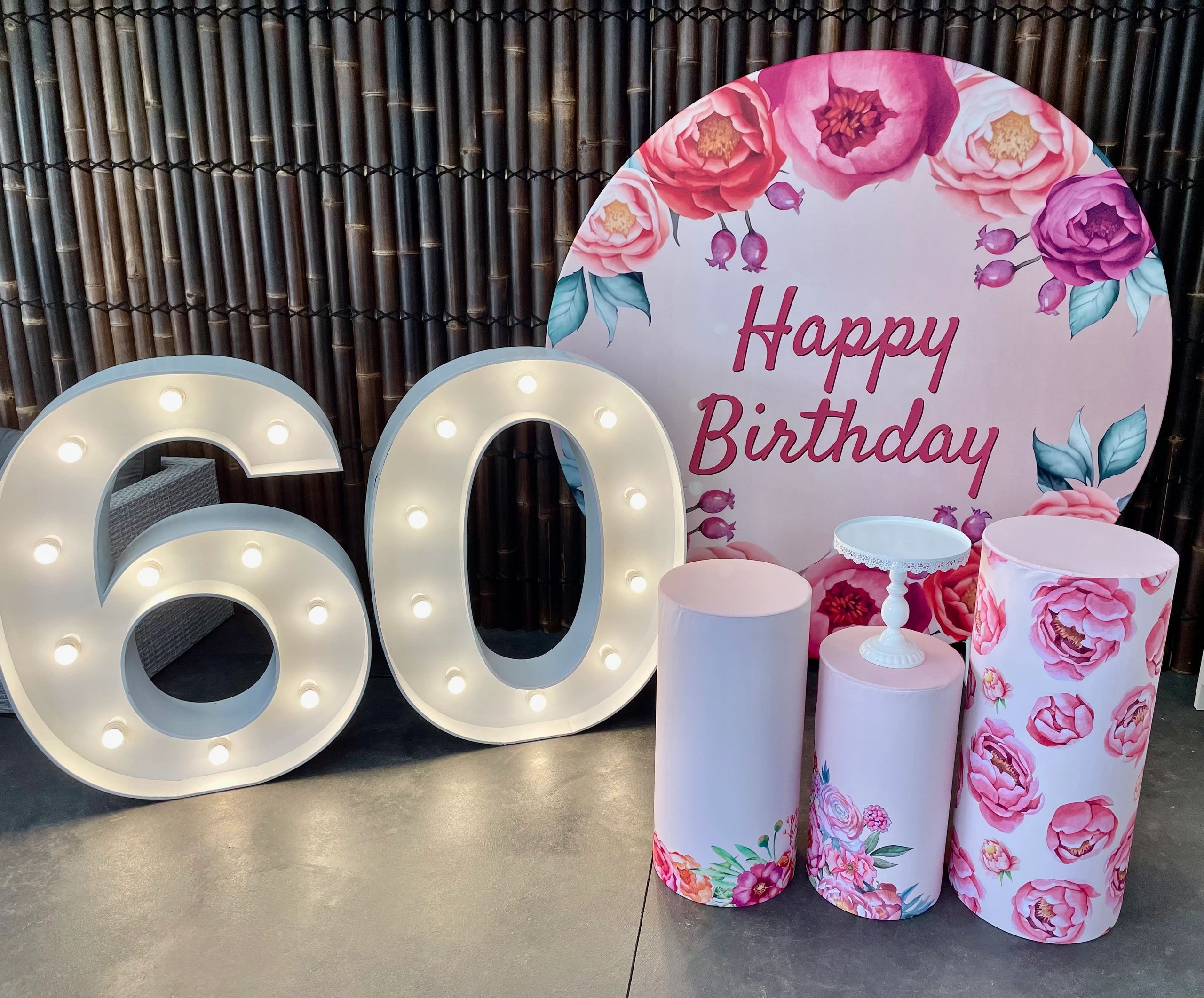Decorative setup for a 60th birthday with floral themes and illuminated numbers.