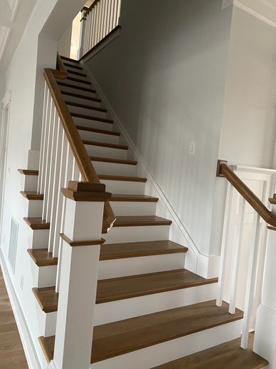 Modern wooden staircase with white railings in a bright home interior.