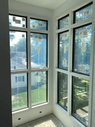 Newly installed large windows in a bright room corner with labels still attached.