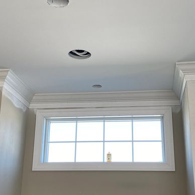 Ceiling with crown molding and a window with a bottle on the sill.