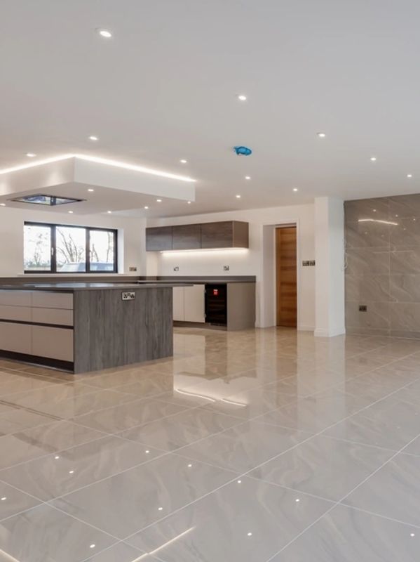 Spacious modern kitchen with sleek cabinetry and glossy tiled floor.