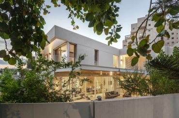 Modern house with large glass windows and surrounding greenery.