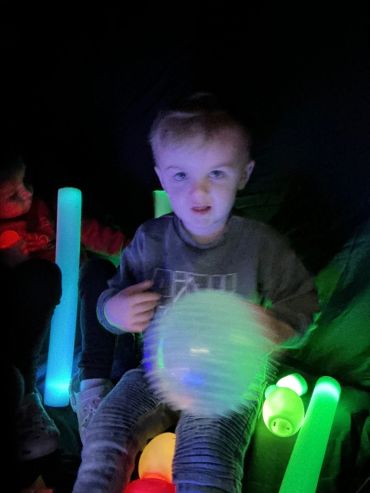 Child playing with glowing toys in a dark room.