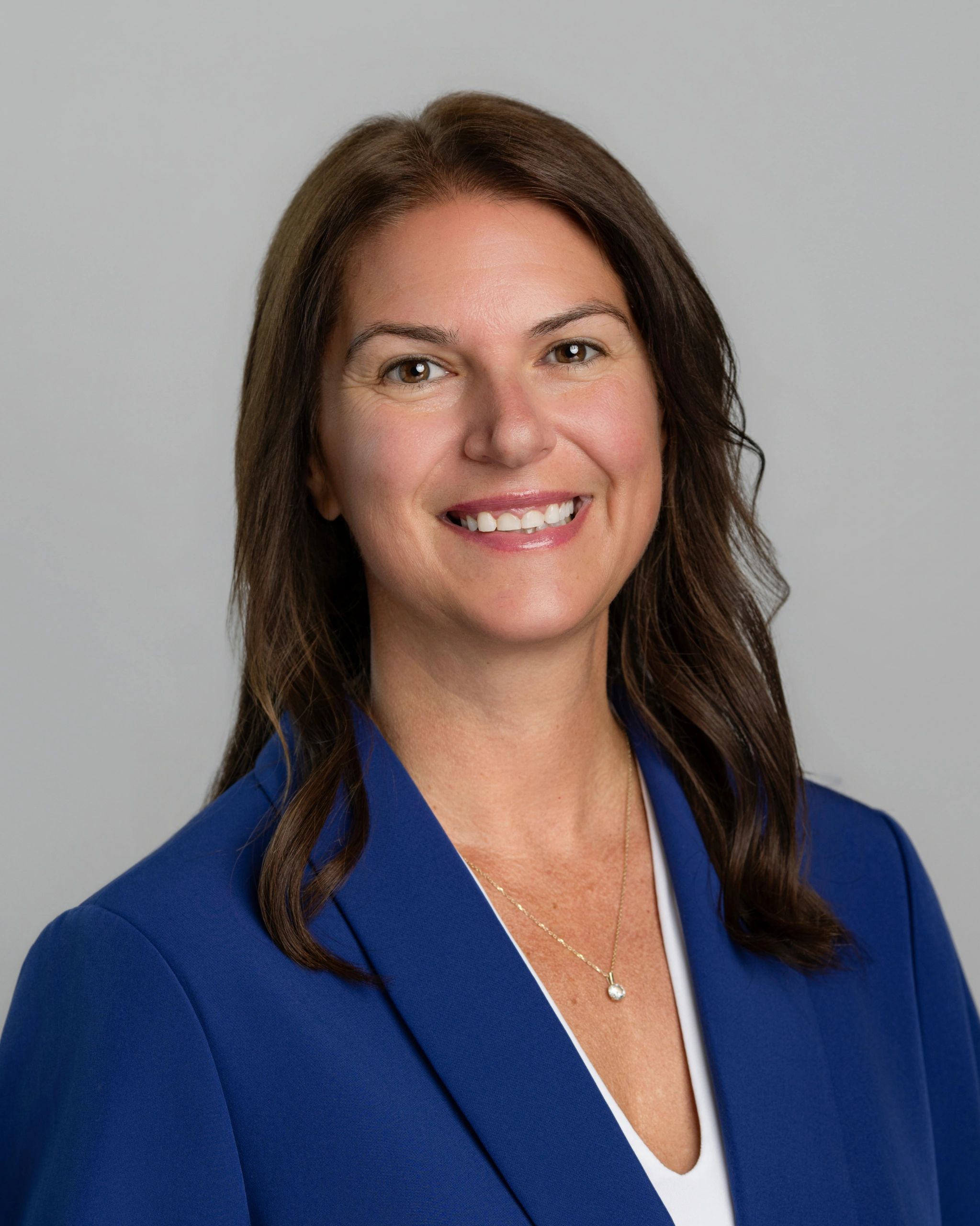 Smiling woman with brown hair in blue blazer.