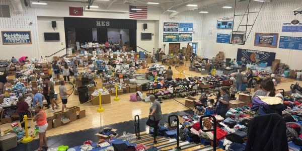 Community members sorting donations in a gymnasium filled with supplies and clothing.