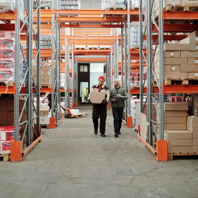 Two workers walking in a large warehouse carrying boxes ORLMAR EXPORTS logistics