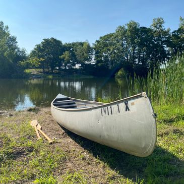 Canoe by a calm lake with green trees.