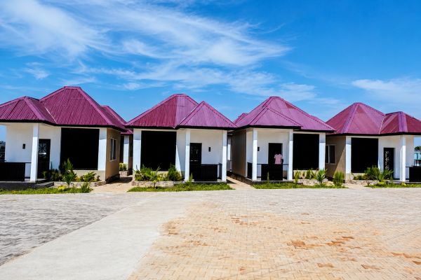 Row of modern houses with red roofs under a clear blue sky.