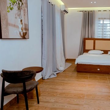 Minimalist bedroom with wooden flooring and simple furnishings.