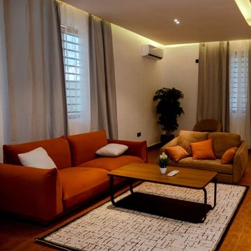 Cozy living room with orange and brown sofas, a wooden coffee table, and warm lighting.