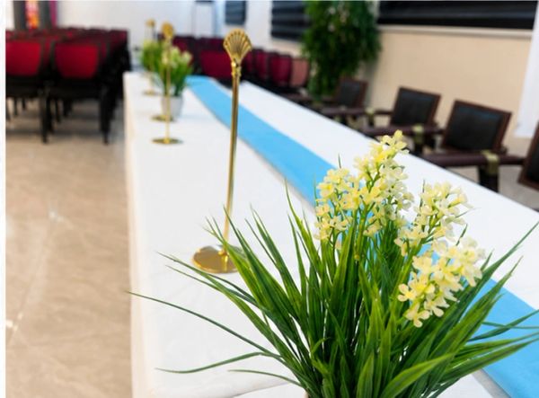 Close-up of yellow flowers on a decorated conference table with blue runner.
