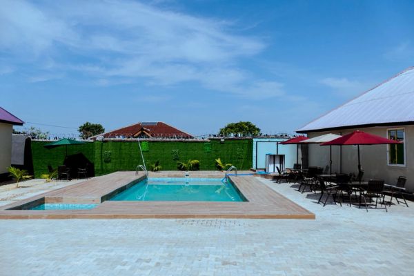 Outdoor pool area with tables, chairs, and umbrellas under a clear blue sky.