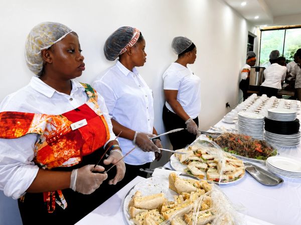 Catering staff serving sandwiches and salads at an event buffet.