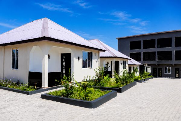 Modern white houses with landscaped gardens under a clear blue sky.