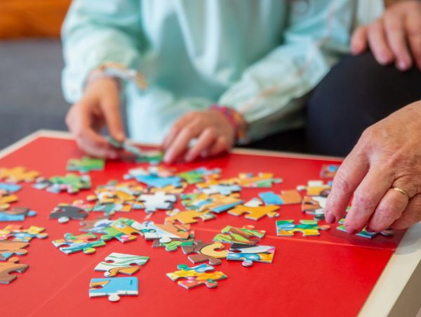 Kids putting a puzzle together on a red table