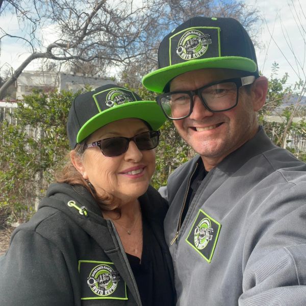 Smiling couple wearing matching hats and jackets outdoors.