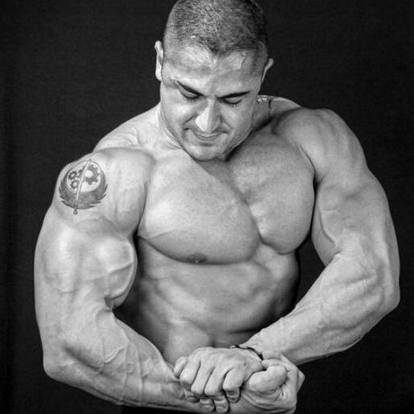 Black and white photo of a muscular man flexing his arms and chest.