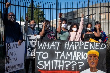 Protesters raise fists holding signs demanding justice for Tamario Smith.